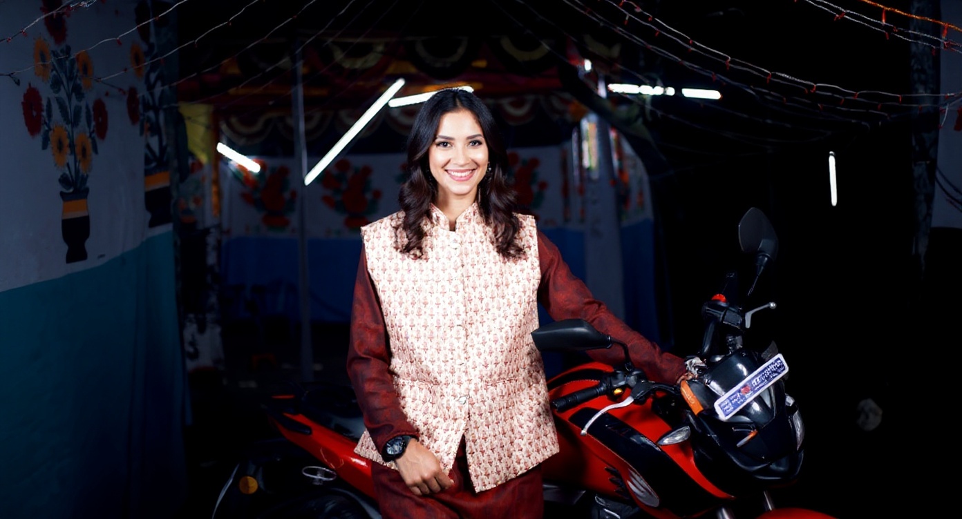 A woman in a traditional outfit is standing next to a red motorcycle.